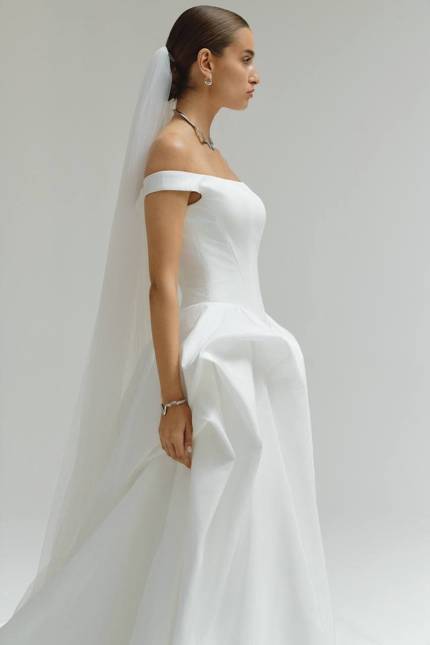 Profile of the model in an off-shoulder Althea Lumina gown with a long veil