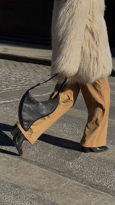 Crescent bag swinging with camel trousers in motion
