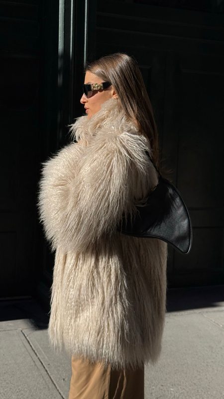 Profile of the cream fur coat with the crescent bag on the shoulder