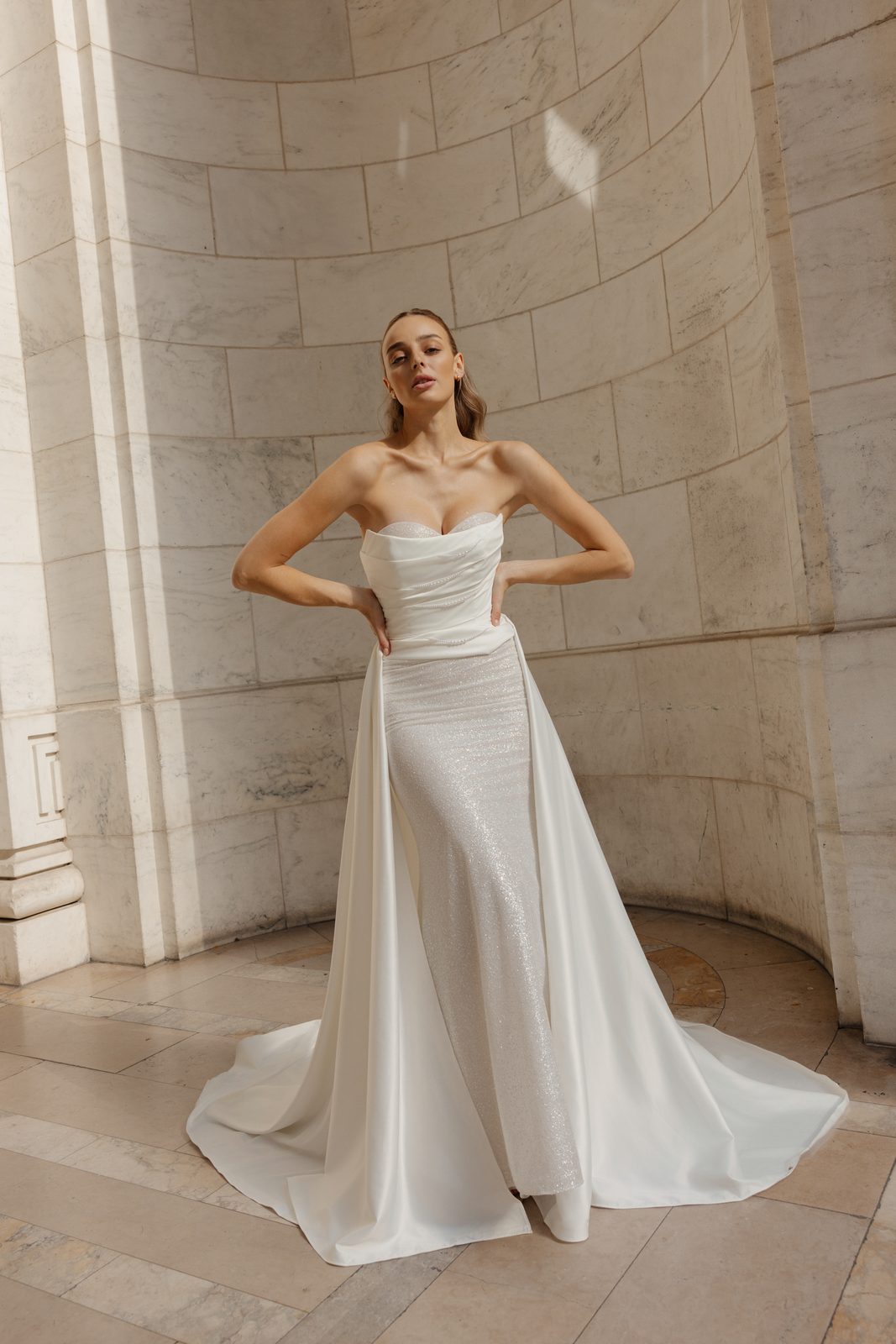 Model in a Sienricher gown with an overskirt in a marble library hall