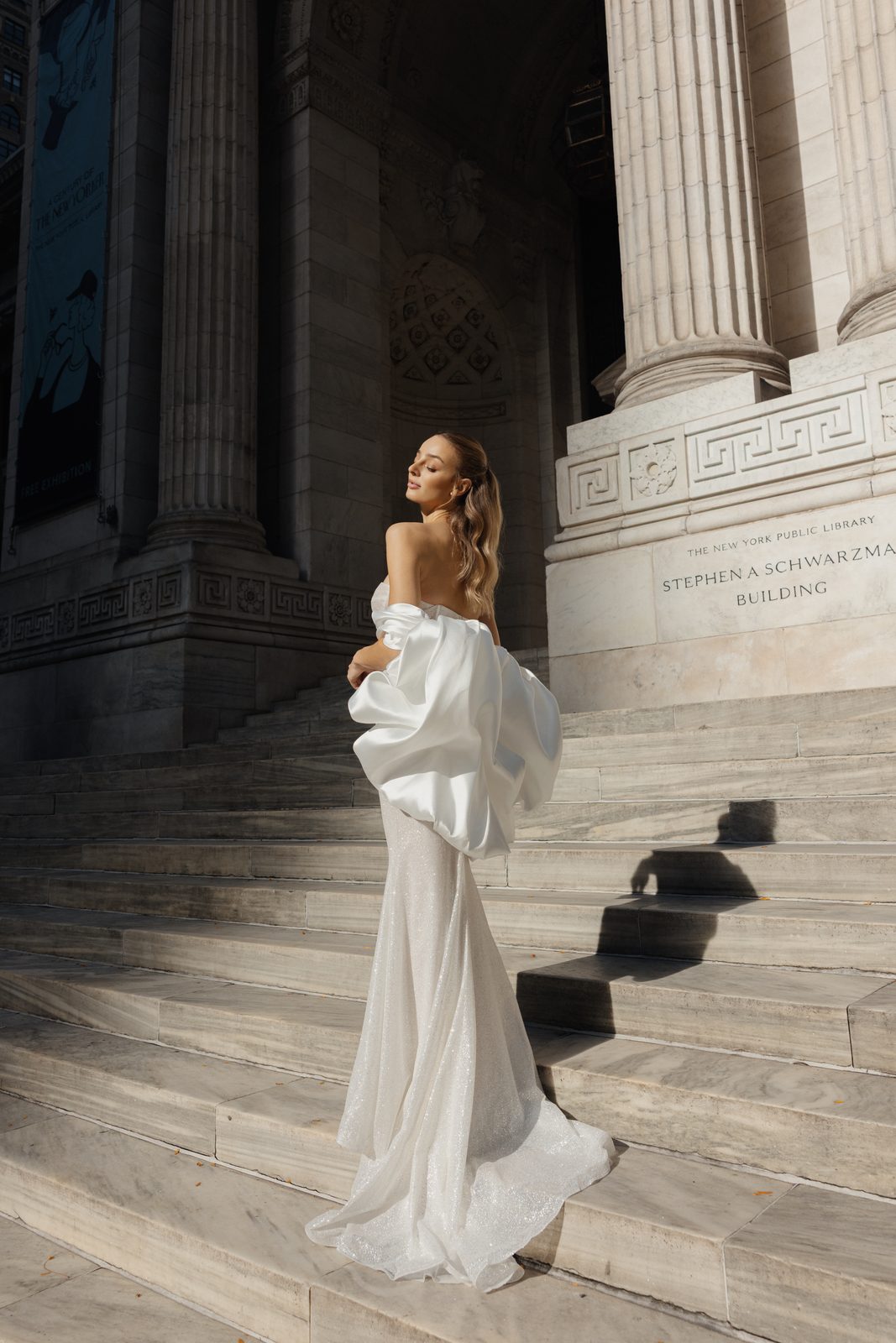 Model in a Sienricher bridal gown with a satin bow on the steps of a landmark library in Manhattan