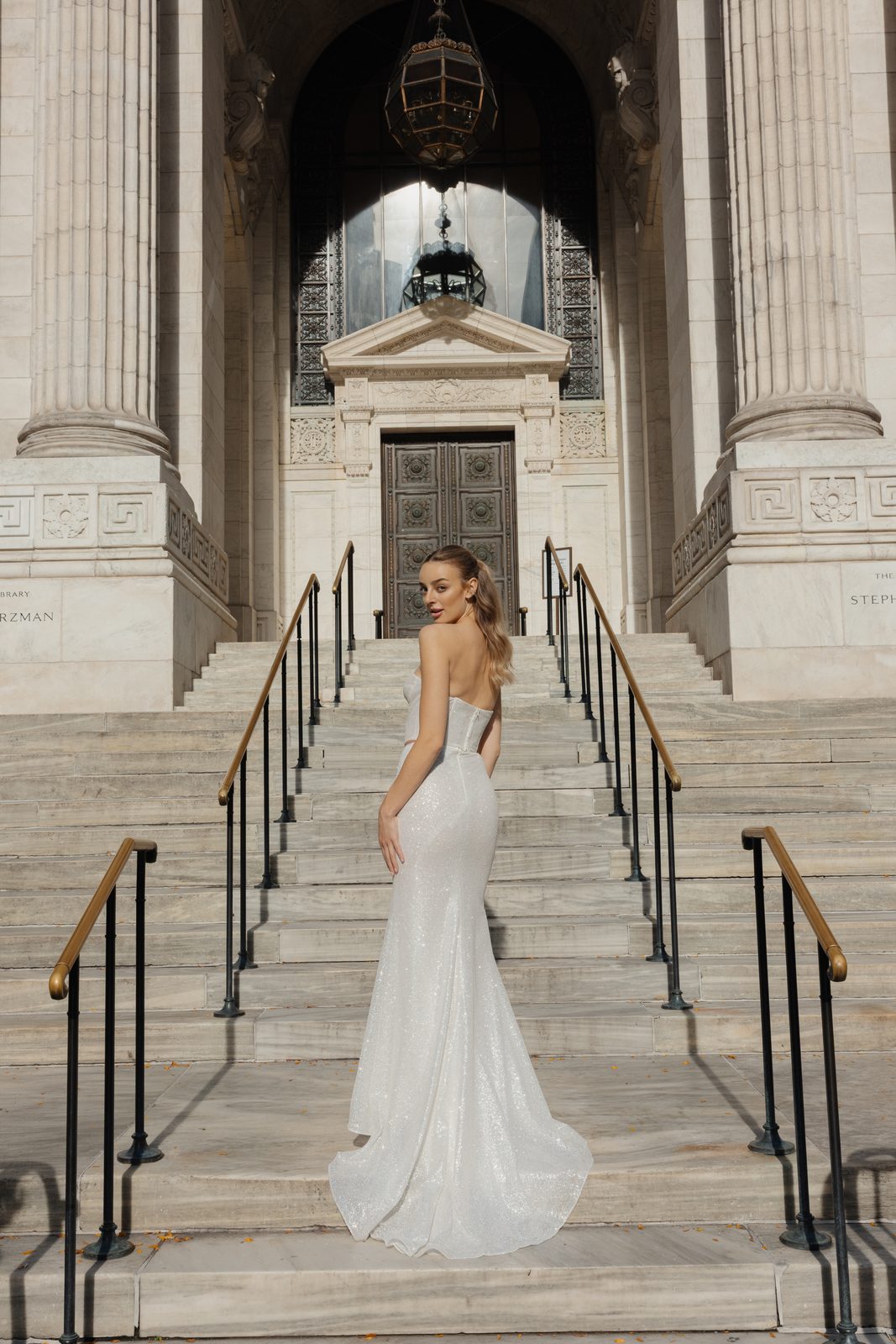 Model in a fitted Sienricher gown with a long train on the library steps